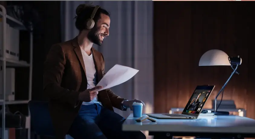 Мъж работи вечер на бюро с ThinkPad лаптоп